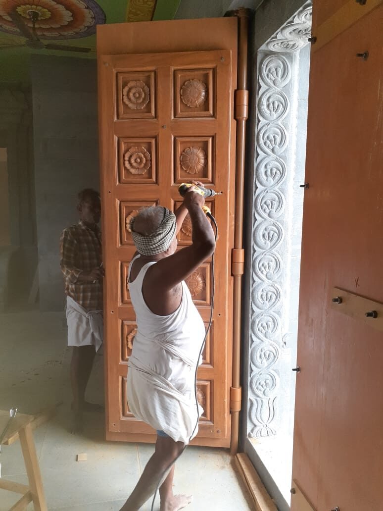 Craftsman finishing a large carved wooden door